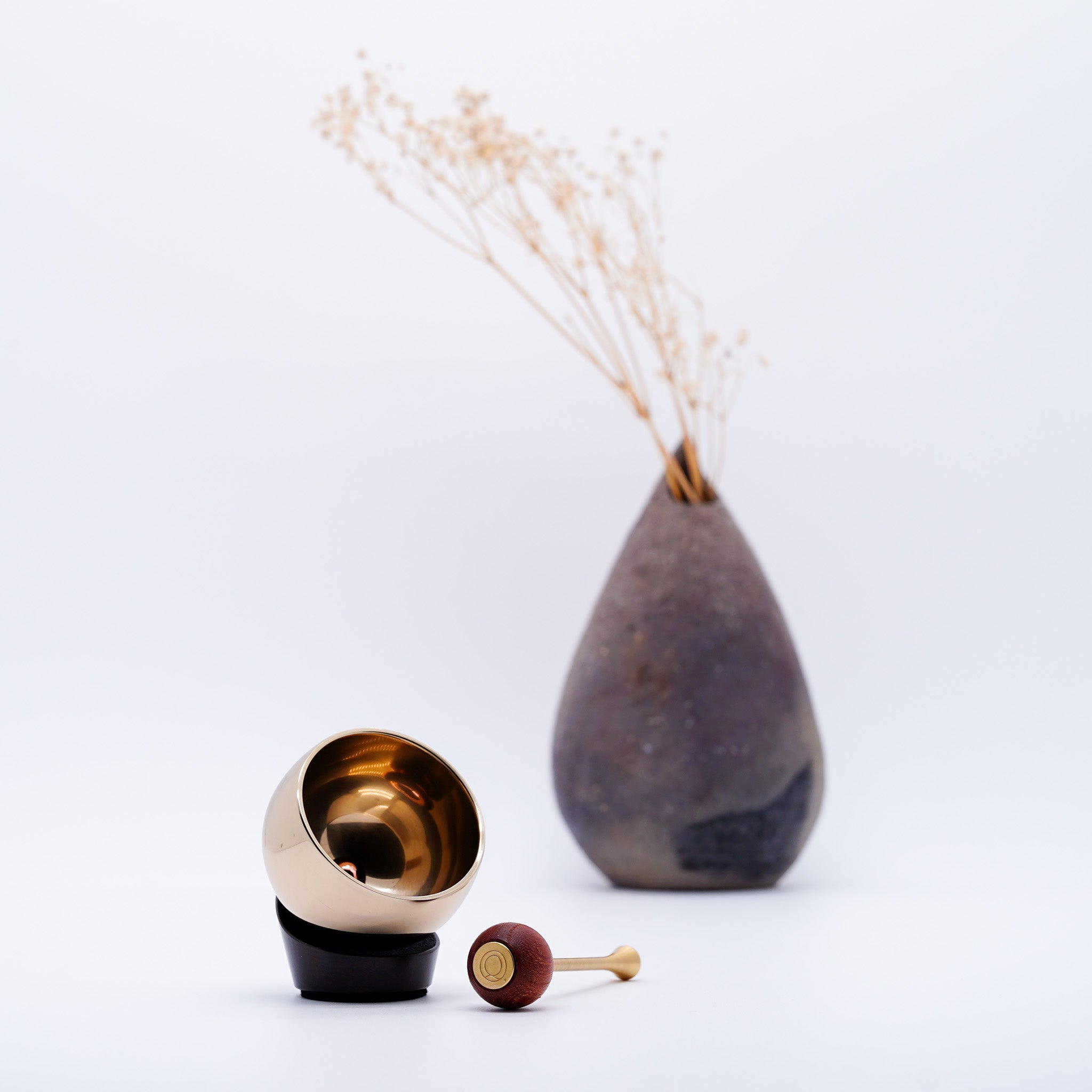 Astrolin dark bronze orin bell by Yamaguchi Kyujo styled with a stoneware vase and dried flowers, Takaoka, Japan