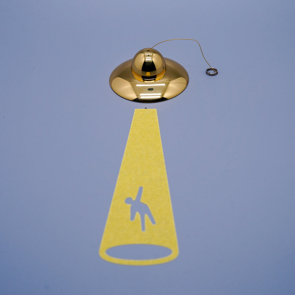 UFO disc-shaped brass wind chime in gold close-up showing cord and hanging mechanism, by Nousaku, Takaoka, Toyama, Japan
