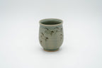 Matsunaga Soma Eight Horses cup with dark running horses on pale green glaze, a rounded body and a gently flared rim.