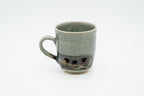 Rear view of the Soma mug with its handle on the left, showing plain crackle glaze and heart-shaped openings near the base.