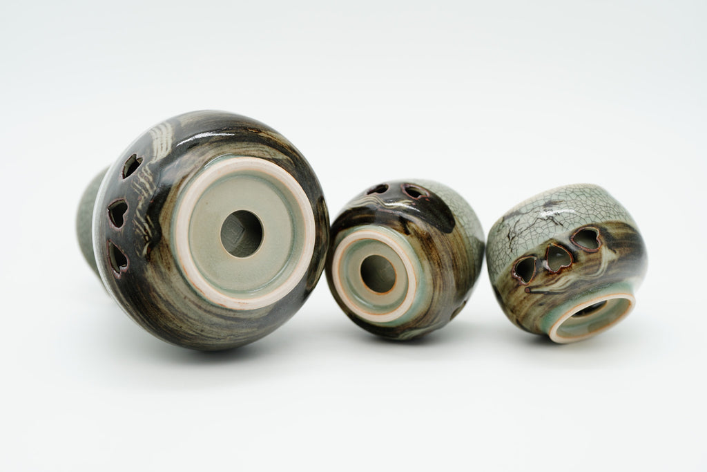 Soma sake carafe and cups tipped onto their sides, showing circular openings in their recessed bases.