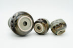 Soma sake carafe and cups tipped onto their sides, showing circular openings in their recessed bases.