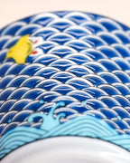 Close-up of the Good Fortune Chidori cup’s overlapping blue wave pattern, yellow bird and pale blue waves.
