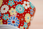 Close-up of the Good Fortune Umekiku cup’s colourful flowers and white dots on a glossy red surface.