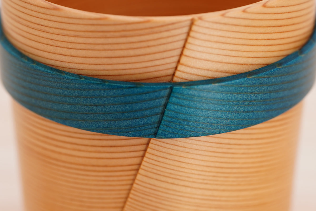 Close-up of wood grain and overlapping seams across the Odate Magewappa Ring Cup’s blue ring and upper rim.