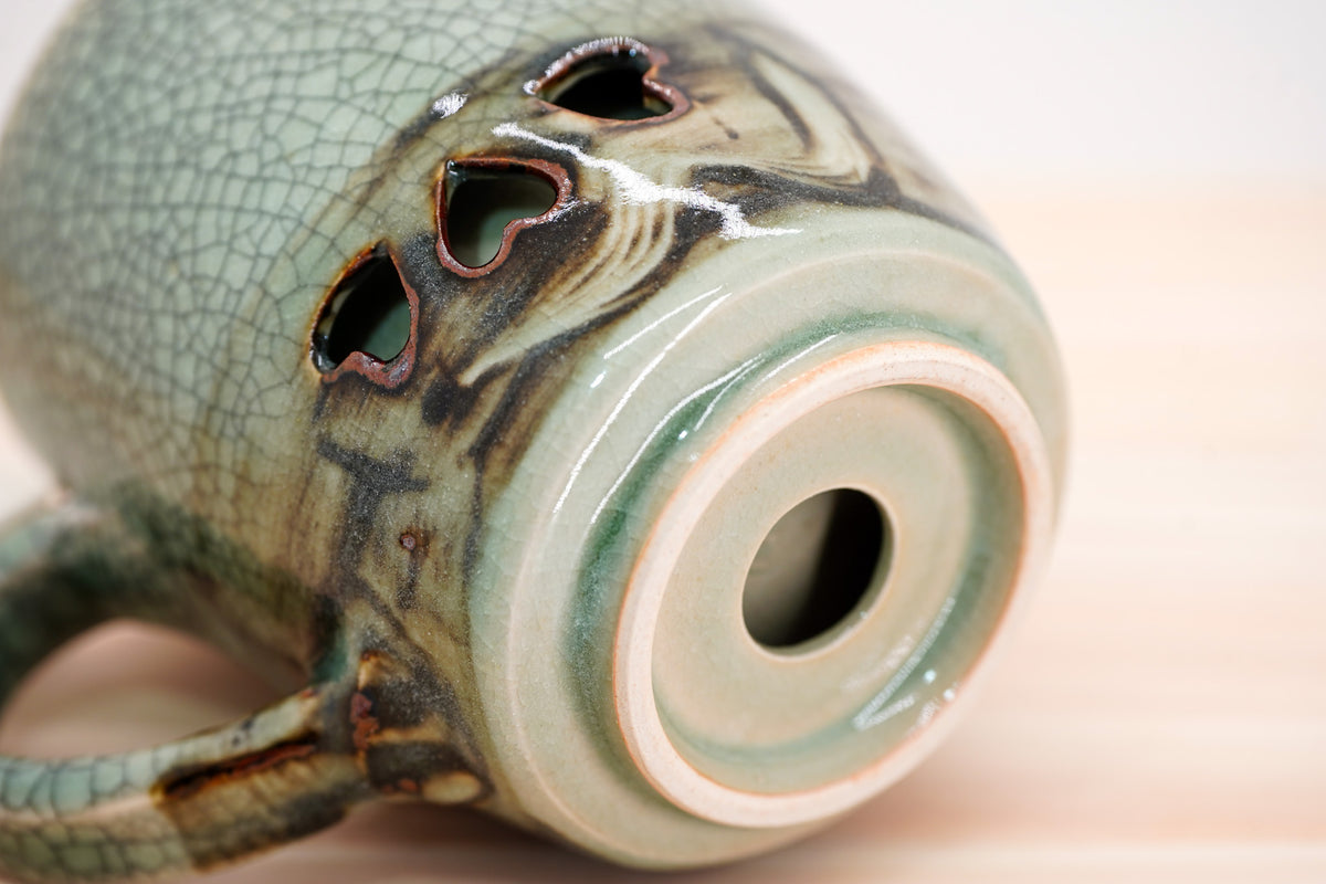 Close-up of the Soma mug’s recessed base with a circular opening, pale foot ring and heart-shaped cutouts above.