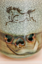 Close-up of a running horse on crackled grey-green glaze above three heart-shaped openings. Soma ware cup. 