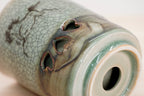 Close-up of heart-shaped openings and swirling brown and green glaze near a Soma cup’s base.