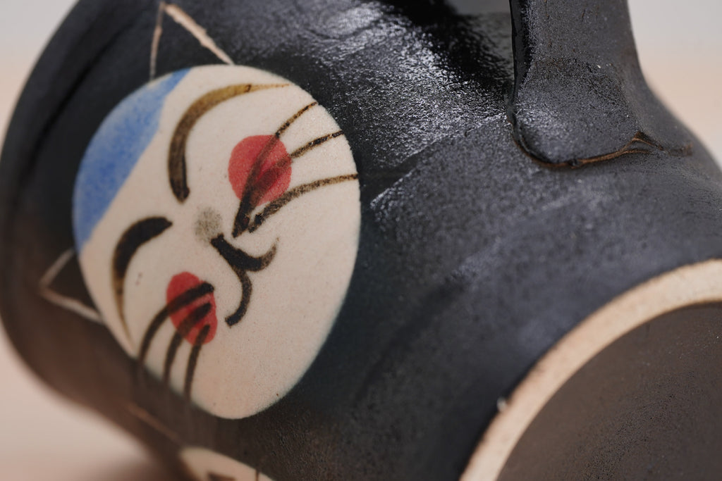 Close-up of a smiling cat face with red cheeks on the black Couple Cats mug’s textured surface.