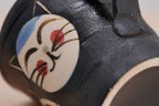Close-up of a smiling cat face with red cheeks on the black Couple Cats mug’s textured surface.
