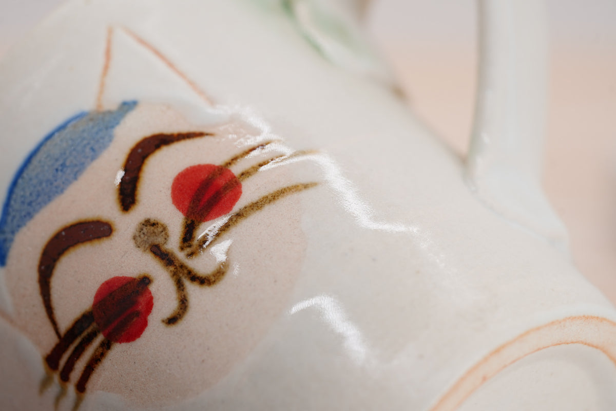 Close-up of a cat’s red cheek and whiskers on the cream Couple Cats mug’s glossy surface.