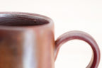Close-up of the Bizen mug’s rounded rim, dark textured interior and handle attachment.