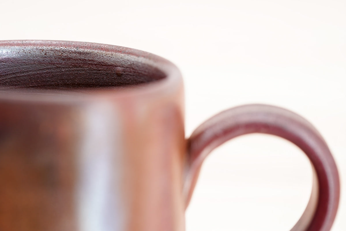 Close-up of the Bizen mug’s rounded rim, dark textured interior and handle attachment.