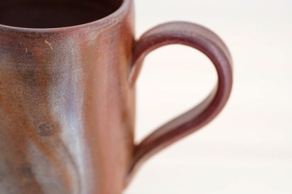 Close-up of the Bizen mug’s curved loop handle and mottled brown surface.