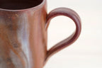 Close-up of the Bizen mug’s curved loop handle and mottled brown surface.