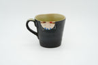 Reverse of the black Couple Cats mug showing an upside-down cream cat face just below the rim.