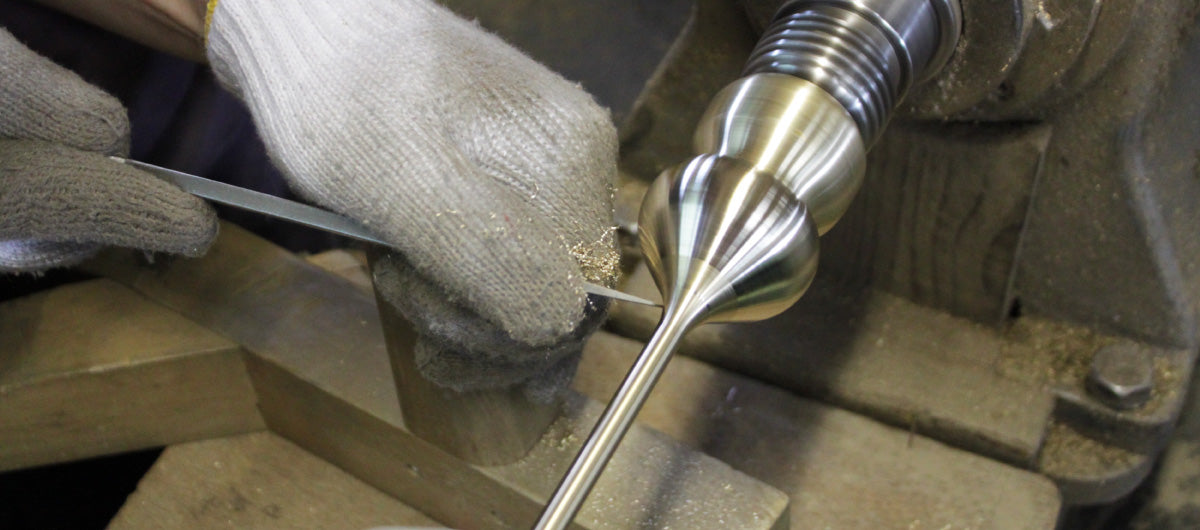 Close-up of a metalworking process with a tool and gloved hands of Nousaku workshop